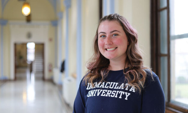 Student in college hallway with Immaculata shirt