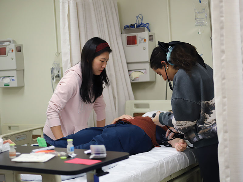 Two nursing students assist patient in disaster drill.