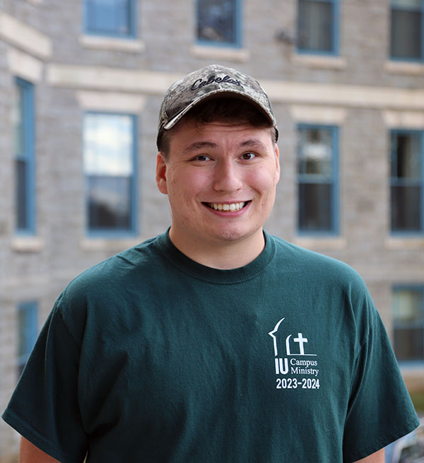 Young man in baseball cap in front of college building