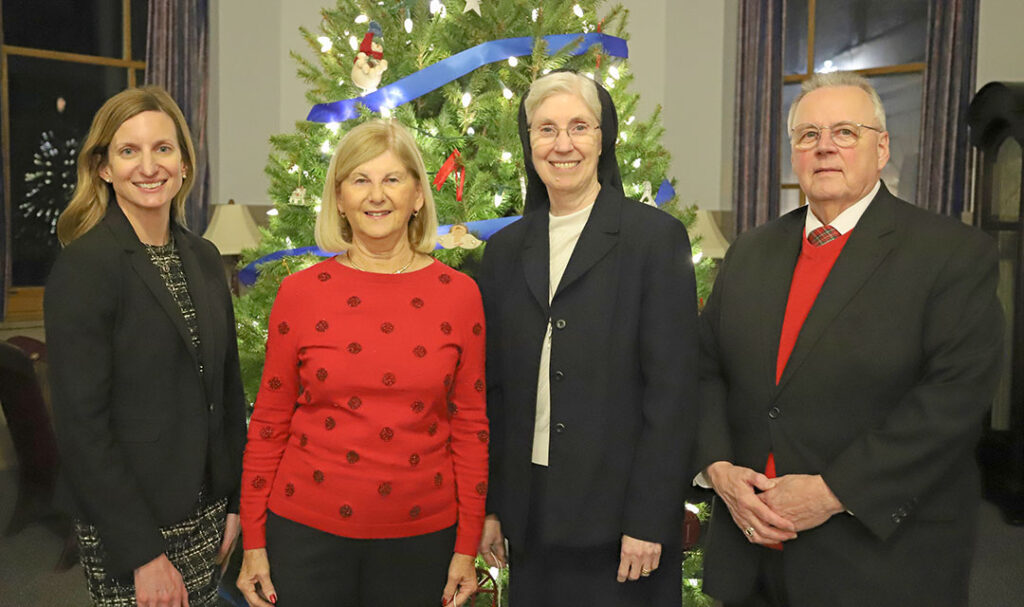 Four people at event, in front of a Christmas tree