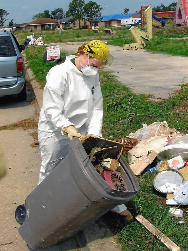 Person in protective gear cleaning trash from hurricane