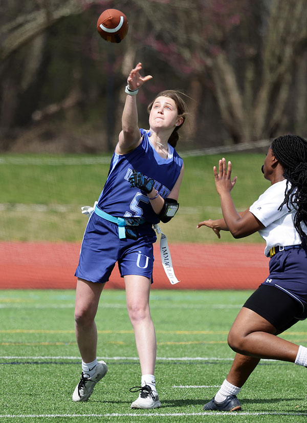 Woman throwing a football in flag football game.