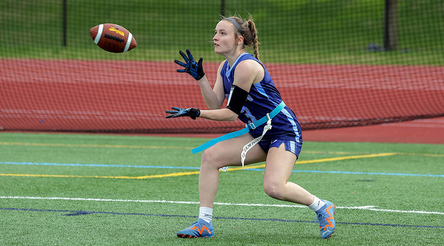 Woman catching a football in flag football game.