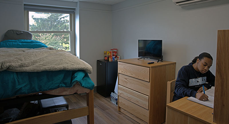 Student in dorm room, sitting at desk