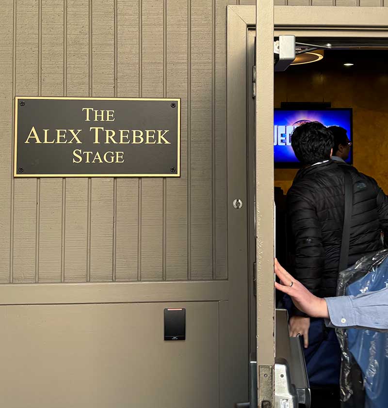 People going through door next to sign that says "Alex Trebeck Stage"