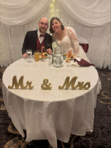 Bride and groom sitting at table with sign saying Mr. and Mrs.
