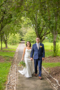 Bridge and groom walking down tree-lined path