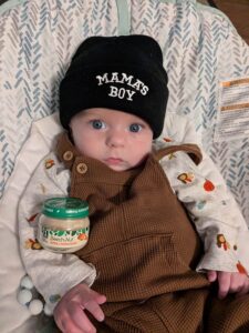 Baby wearing knit cap with text Mama's Boy