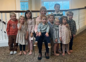 Older woman surrounded by nine young children
