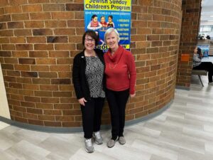 Two women standing in front of brick wall