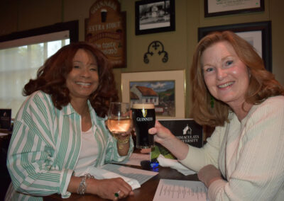 Two women at a table holding up drinks