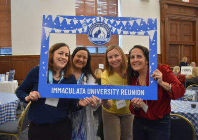 Four women holding sign Immaculata University Reunion