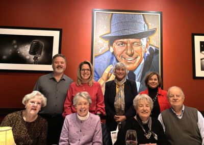 Group of people in restaurant in front of painting of Frank SInatra