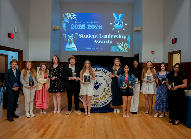Group of people holding plaques in front of screen saying "Student Leadership Awards"