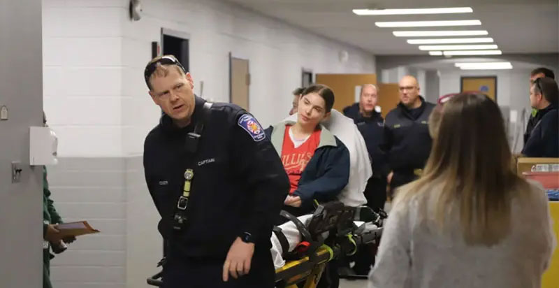 EMTs roll stretcher down hallway