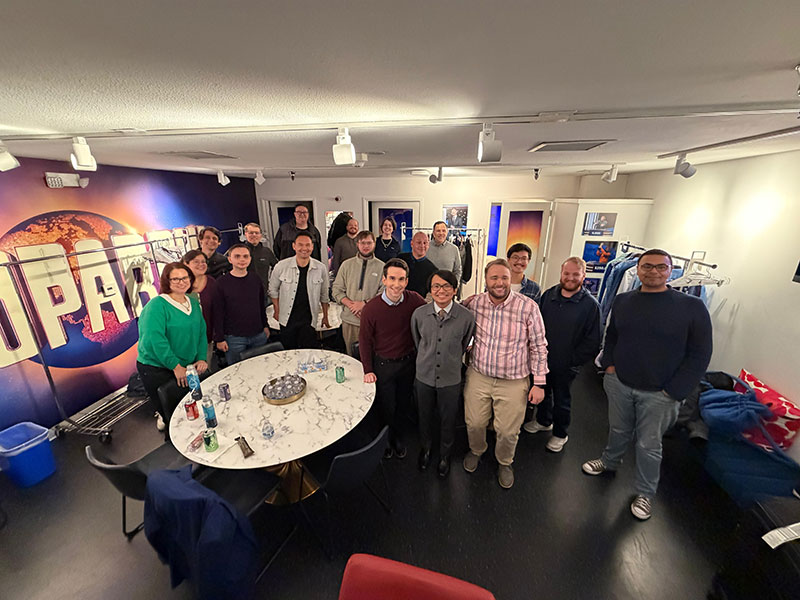 Group of people in room with Jeopardy illustration on wall behind them
