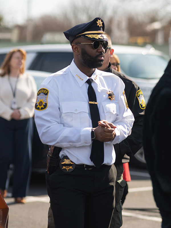 Man in police uniform standing outside with other people