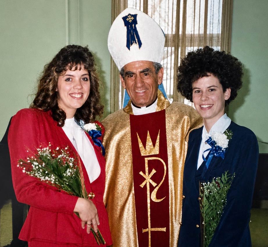 An archbishop standing next to two young women